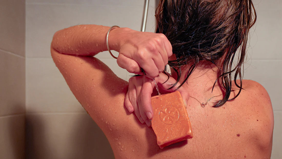 Utilisation d’un savon solide artisanal naturel sous la douche, appliqué sur le dos