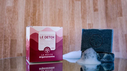 Savon solide artisanal naturel Le Détox pour le corps et les cheveux, présenté avec son emballage et une mousse naturelle