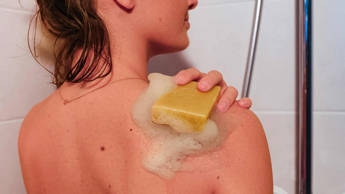 Savon solide artisanal naturel utilisé sous la douche pour le soin du corps, avec mousse sur la peau