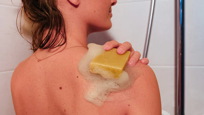 Savon solide artisanal naturel utilisé sous la douche pour le soin du corps, avec mousse sur la peau